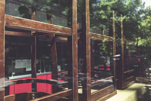 Oude stoelen van een restaurant gestapeld achter een raam — Stockfoto