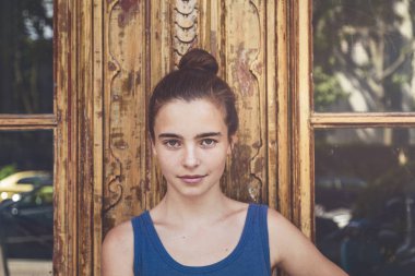 Eski bir ahşap kapının önünde gülümseyen bir genç kadının portresi