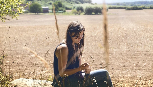 Porträt einer nachdenklichen, traurigen jungen Frau auf einem Felsen sitzend — Stockfoto