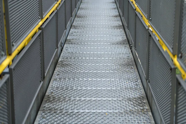 Puente peatonal de metal en una instalación industrial con barandillas amarillas —  Fotos de Stock