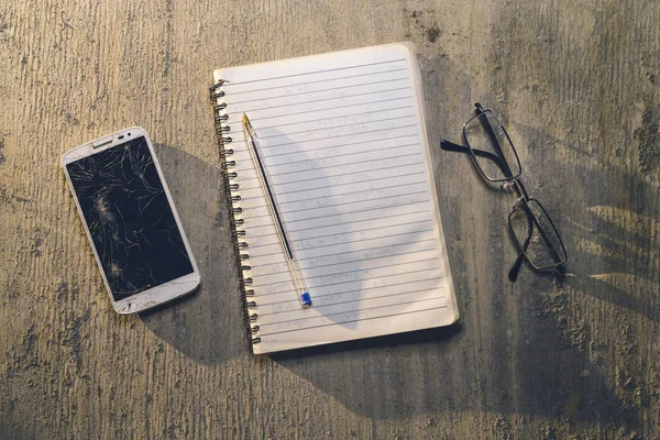 Top view of an old table with mobile, pad, pencil and glasses — Stock Photo, Image