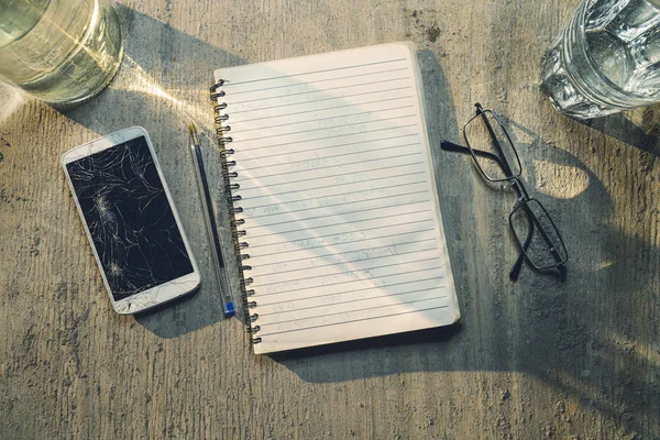 Top view of an old table with mobile, pad, pencil and glasses — Stock Photo, Image