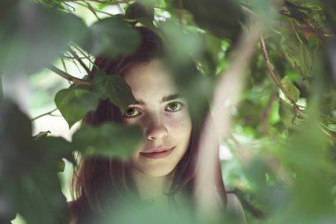 bulanık yaprakları kaplı genç bir gülümseyen kadının portresi