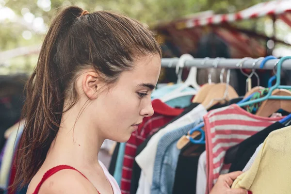 young woman browsing clothes on a flea market
