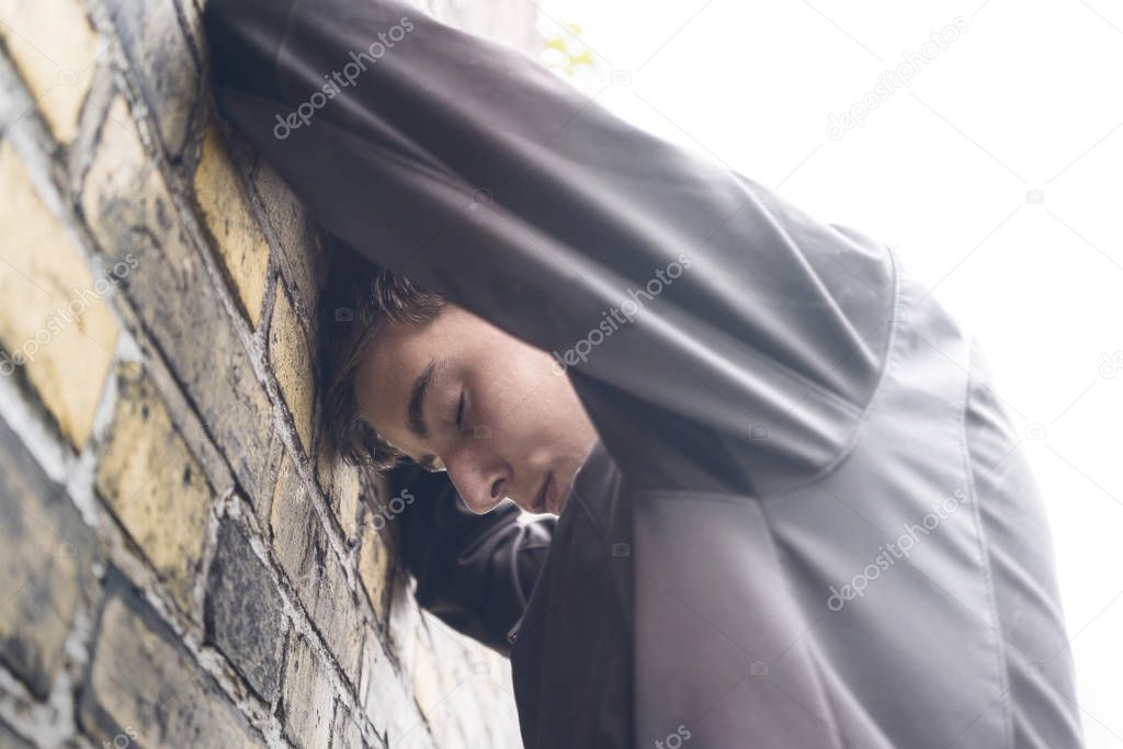young man standing with his head against the wall