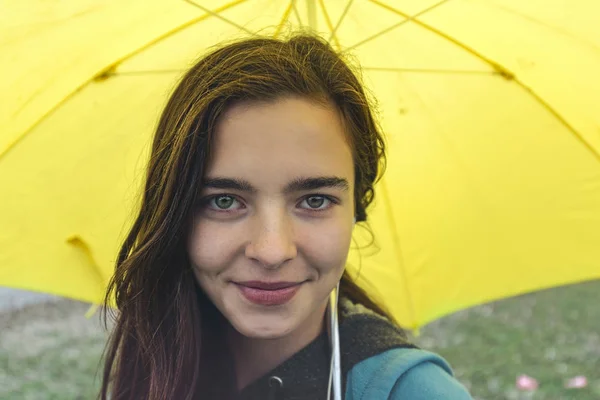 Портрет улыбающейся молодой женщины с желтым зонтиком — стоковое фото