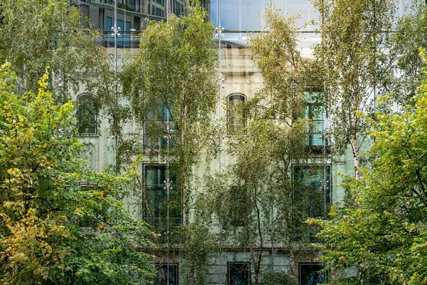 Oud Huis Achter Een Moderne Glazen Gevel Met Bomen Voorgrond — Stockfoto