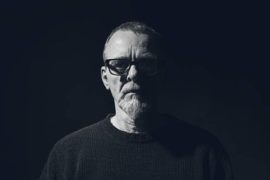 Gözlüklü ve sakallı ciddi bir adamın siyah beyaz portresi.