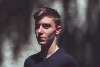 Gölgede duran kendine güvenen bir gencin portresi.