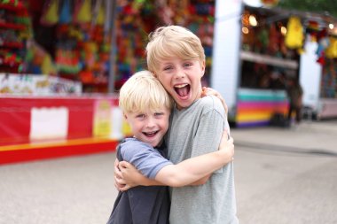 İki mutlu çocuk gülümseyen ve küçük bir kasaba Amerikan karnaval, midway games tarafından sarılma