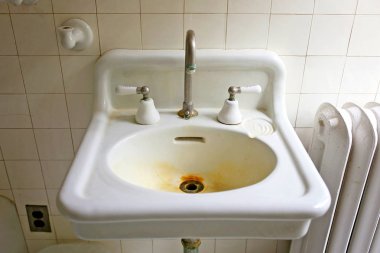 Eski bir vintage, orijinal 1920 's çiftlik evi porselen banyo lavabo pas lekeleri ile drenaj arkasında bir beyaz çini duvar arka plan.