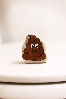 Kaka bir güler yüz ile bir banyo kapalı tuvalete oturuyor gibi bir taş boyanır.