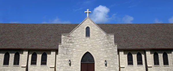 在一个古老的石头教堂一侧的尖顶上的小十字 并在彩色玻璃窗上的一排 — 图库照片