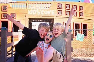 Erkek ve kız kardeşlerim olan mutlu gülümseyen çocuklar bir grup oynuyor dışarıda parkta bir yaz gününde.