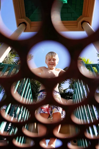 Garotinho sorrindo enquanto olha através de círculos na plataforma em — Fotografia de Stock