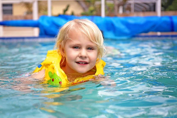 Lille barn iført Oppustelig redningsvest læring at svømme i - Stock-foto
