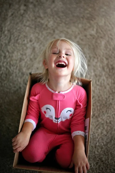 Petit enfant riant jouant dans une grande boîte en carton à la maison — Photo