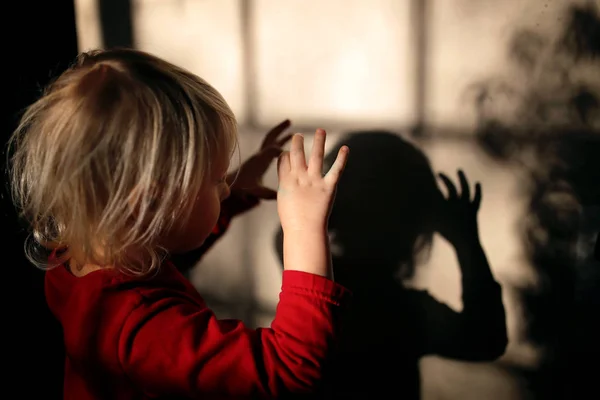 Pequeño niño haciendo títeres de sombra con los dedos en la pared de su —  Fotos de Stock