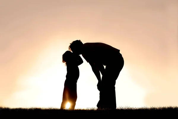 Silhueta de criança beijando seu pai ao pôr do sol em um Soma — Fotografia de Stock