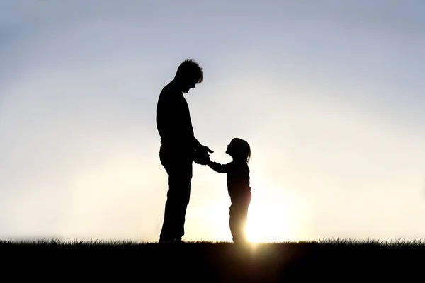 Silueta otce a jeho šťastného malého dítěte držícího se za ruce — Stock fotografie