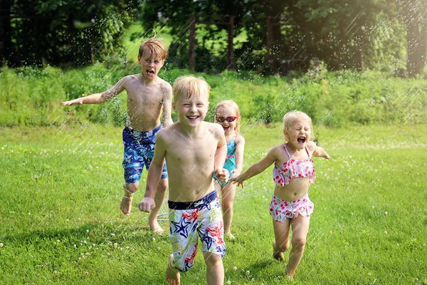 Grupa szczęśliwych małych dzieci uśmiecha się, gdy biegną przez — Zdjęcie stockowe