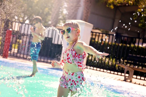 Enfant en bas âge courant à travers les arroseurs d'eau à éclaboussure extérieure — Photo