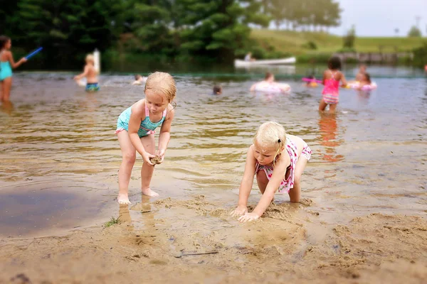 Dwie małe dziewczynki bawiące się w wodzie i piasku na plaży na — Zdjęcie stockowe