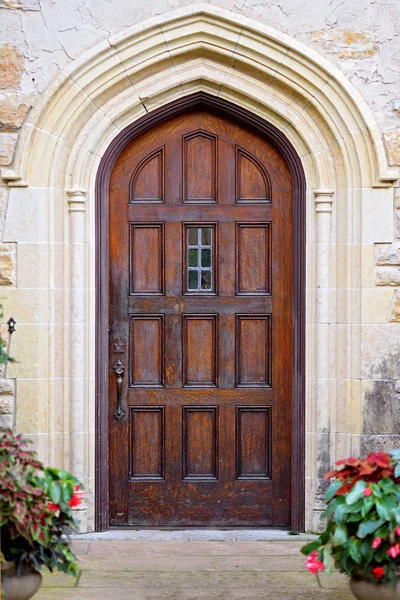 Vecchia porta in legno con porta ad arco su edificio storico in pietra — Foto Stock