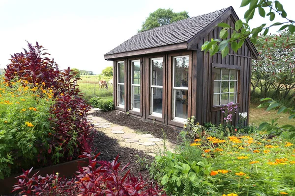 在乡间一个茂盛的夏园里 一个古老的木制花园小屋在一个马场旁边 四周环绕着红石榴莲和科斯莫的花朵 — 图库照片