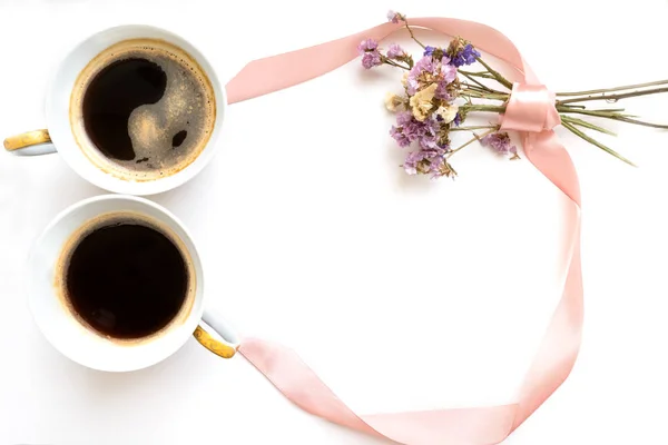 Two cups of coffee in the form of a figure 8. Pink ribbon with flowers. Flat lay, top view. Valentines and 8 March Mother Womens Day concept