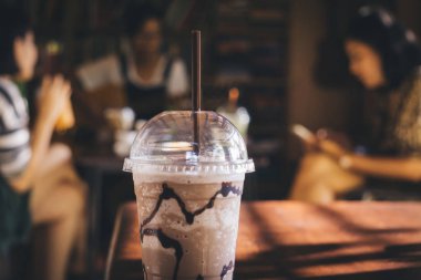 Bir konuşma sahip insanlar grubu ile plastik buzlu çikolata fincan seçici odak, gitar çalarken, bir kitap okuma ve bulanık arka plan olarak birbirleri ile harcanan zaman zevk. Kahve zamanı konsepti.