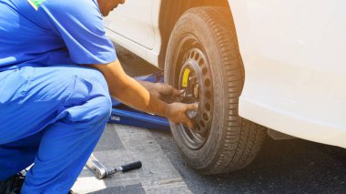 Araba tamircisi yolda düz lastikler yerine. Mavi hidrolik araba zemin krikolar araba ve tekerlek anahtarı yakın arka planda yerleştirilen kaldırın. Araba tamiri, sevice motor ve bakım konsepti.