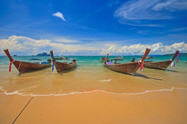 Ao Nang plaj, Krabi, Tayland güzel kum plaj ve renkli bulutlu mavi gökyüzü arka plan ile Tay geleneksel ahşap longtail tekne.
