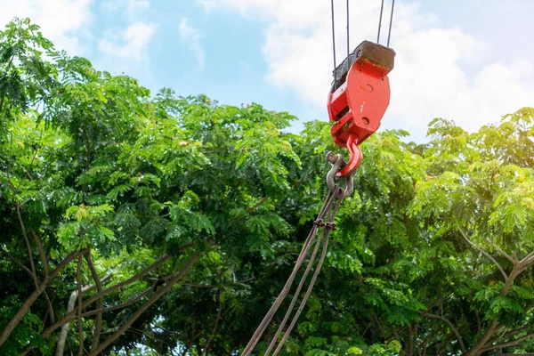 Mobile construction cranes with red lifting steel crane hook, swivel joint and connection steel sling. Blurred beautiful tree background. Mobile cranes installing the structures outdoor. Building and construction equipment.