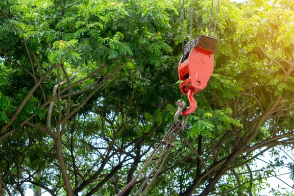 Mobile construction cranes with red lifting steel crane hook, swivel joint and connection steel sling. Blurred beautiful tree background. Mobile cranes installing the structures outdoor. Building and construction equipment.