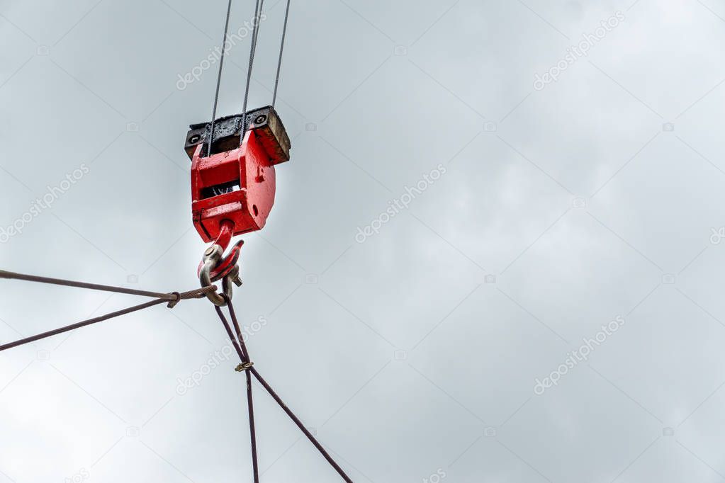 Mobile construction cranes with red lifting steel crane hook, swivel joint and connection steel sling in sunny day with clouds background. Mobile cranes installing the structures outdoor. Building and construction equipment.