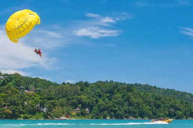 Parasailing Patong Beach, Tayland popüler bir su sporudur. Renkli paraşütle uçan insanlar arka planda açık mavi bir gökyüzü ile sürat teknesi tarafından çekildi. Parasailing su eğlence.