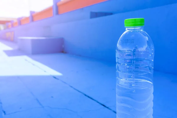 Drinking plastic bottles with clean water on blue concrete floors background with copy space. Drink water while exercising in fitness, gym or stadium for health and well-being concepts.