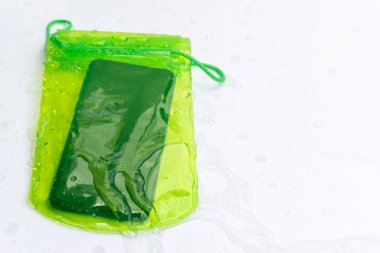Beyaz arka plan üzerinde su damlacıkları ile yeşil su geçirmez cep telefonu durumda. Pvc zip kilit torbası cep telefonu veya önemli öğeleri sudan korumak. Tayland Songkran su festivali için Konsept.