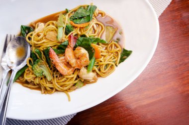 Kırmızı ahşap masa arka plan üzerinde soya sosu, karides, sebze ve mantar ile lezzetli sarı kızarmış erişte kapatın. Tay tavada erişte (Pad See-Ew). Kopyalama alanı ile üstte görünüm.