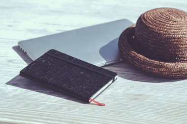 Dizüstü bilgisayar, dizüstü bilgisayar ve hasır şapka ve ahşap tablo 