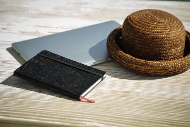 Dizüstü bilgisayar, dizüstü bilgisayar ve hasır şapka ve ahşap tablo 