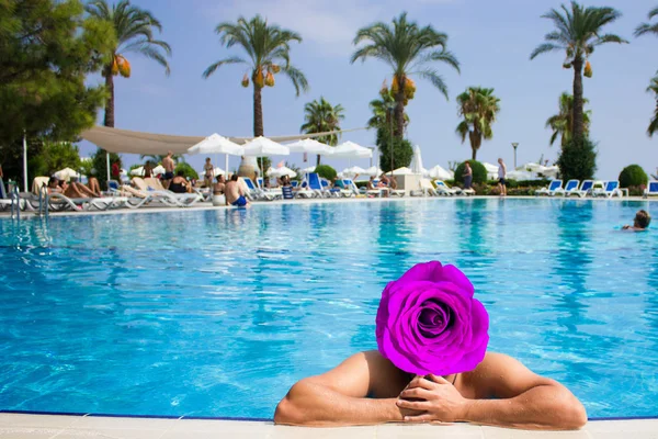 Young wet sexy muscular man posing in the swimming pool