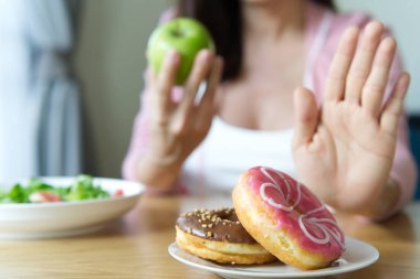 Genç kız abur cubur veya çörek gibi sağlıksız gıda reddetme ve sahip iyi bir sağlık için sağlıklı gıda yeşil elma ve salata gibi seçimi. Diyet ve iyi sağlık kavramı.