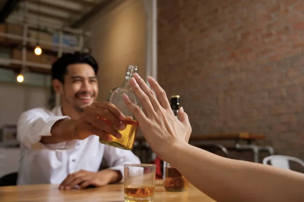Alkol kavramı yok. El ret alkol onu birlikte gece bar restoran içinde içmek için davet etmeye viski şişe tutan tablo karşı tarafında oturan adam görüntüsünü kapatmak.