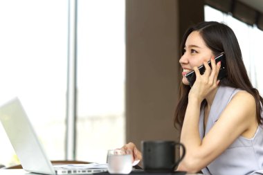 Cep telefonu kafede oturan iş konuşurken Asya akıllı güzel kız. O dizüstü ve fincan kahve masaya koy vardır. O gülümseme ile iyi konuşma vardır. Akıllı çalışma kavramı.