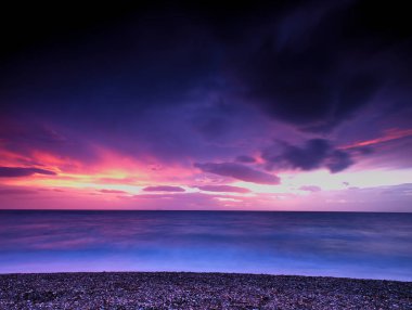 Güzel renkli gökyüzü gün batımında sahilde kış zamanı. Attica, Yunanistan. Suya yansıtan güneş ışık.