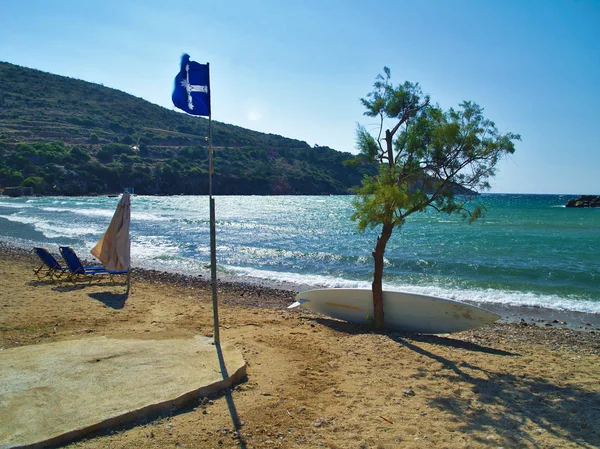 Bella spiaggia bandiera blu, albero e tavola da surf nell'isola di Chios Grecia . — Foto Stock