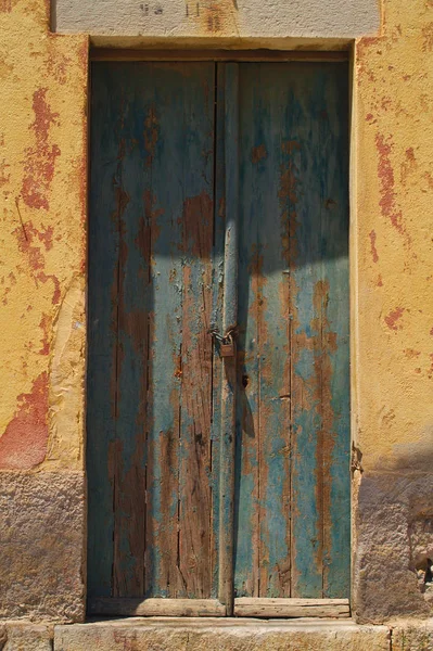 ギリシャ シミ島のカラフルな壁に古い木製のドア 剥離塗料 家の壁 — ストック写真
