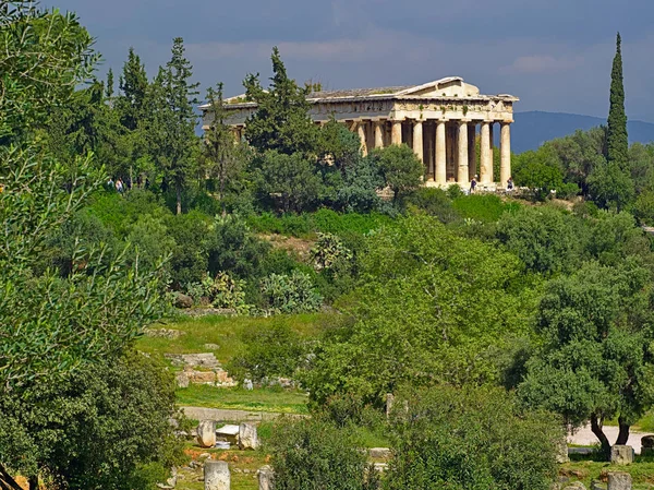 Atina'daki Hephaestus Tapınağı, Yunanistan. Zeytin ve diğer ağaçlar bulutlu gökyüzü, parlak ışık ve antik Yunan tapınağı ile Manzara.